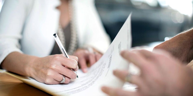 Close up of a person's hand signing a credit document